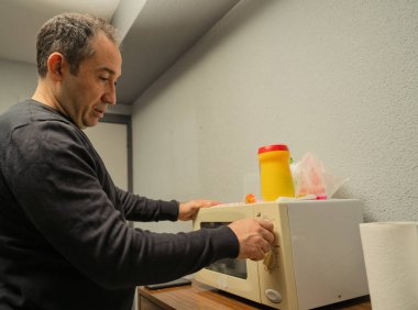Adam mikrodalga fırını açıp yemek hazırlıyor.