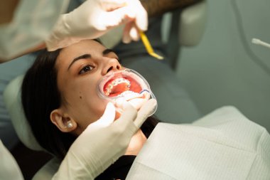 Diş doktorunun muayenehanesindeki hasta diş tellerini kontrol ettiriyor.