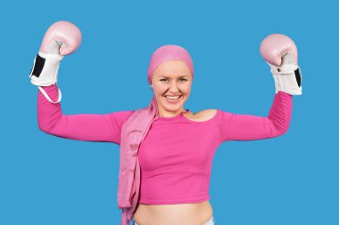 Pembe boks eldiveni ve türban takan kadın göğüs kanseri farkındalığını ve hayatta kalmayı simgeliyor.