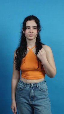 Havluyla gülümseyen güzel bir kadın mavi arka plana karşı yanağına allık sürüyor.