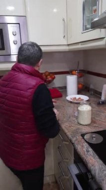 Gri saçlı yaşlı kadın sağlıklı bir yemek hazırlıyor ve tavada sebzeleri karıştırıyor.