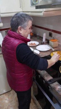 Üst düzey bir kadın modern bir mutfakta ahşap kaşıkla lezzetli bir kaynar çorba karıştırıyor.