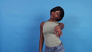 Neşeli Afro-Amerikalı kadın kamerayı işaret ediyor ve mavi arka planda beni çağırıyor.