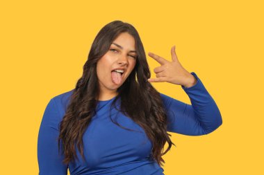 Bir kadın rock 'n' roll el hareketi yapıyor ve dilini dışarı çıkarıyor, eğlence ve isyan ifade ediyor.