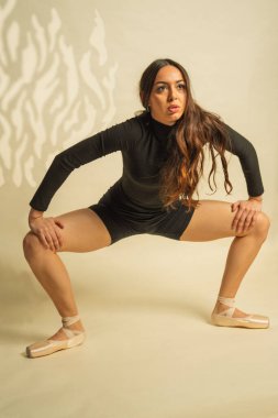 Siyah taytlı ve sivri uçlu ayakkabılı genç kadın bale hareketi yapıyor.