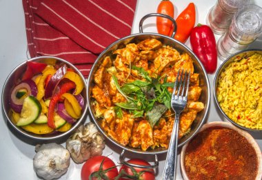 İki saplı metal bir kasede servis edilen tavuk tikka masala.