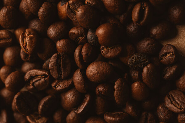 Dark coffee beans close-up on light paper close up.