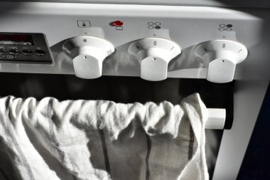 Fırın kapısından sarkan beyaz pamuklu mutfak havlusu.