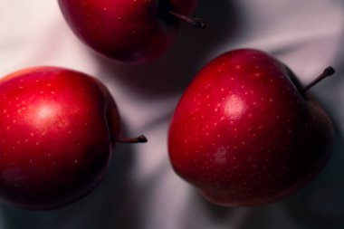 Yumuşak, beyaz bir kumaş üzerinde canlı kırmızı elmalar.