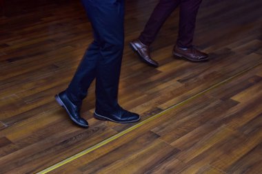 Erkeklerin ayakları ahşap zeminde deri ayakkabılarla dans ediyor.