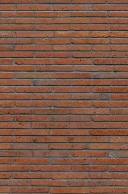 Eski bir kırmızı tuğla duvarın dikey arka planında düzensiz duvarlar ve yaşlanma belirtileri var. Tasarım, doku ve mimari projeler için mükemmel..