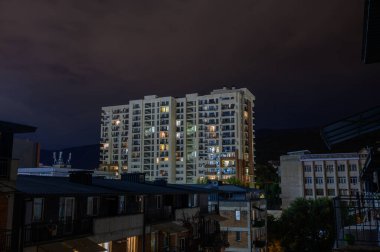 Tiflis 'in Saburtalo bölgesindeki çok katlı bir bina. Açık gökyüzü ve şehir manzarasına karşı balkonları ve pencereleri olan modern mimari.