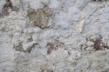 Çatlak, leke ve dengesiz doğal dokusu olan eski bir beton duvarın dikey yakın çekimi. Stok fotoğrafçılığı için mükemmel bir geçmiş..