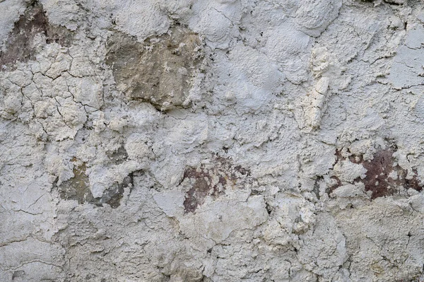 Çatlak, leke ve dengesiz doğal dokusu olan eski bir beton duvarın dikey yakın çekimi. Stok fotoğrafçılığı için mükemmel bir geçmiş..