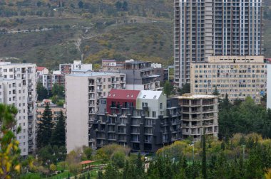 Tiflis 'in Saburtalo ilçesinin panoramik tepe perspektifi, güz ışığında kentsel binalar, sokaklar ve şehir hayatı.