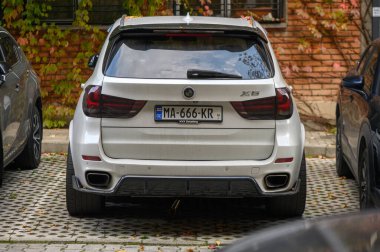 Tiflis, Gürcistan 10.23.2025 Beyaz BMW X5 bir konut binasının yakınına park edilmiş, araba detayları, kentsel çevre ve mahalle içeriği, otomotiv ve şehir projeleri için ideal.