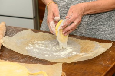 Kadın Napolyon keki için hamuru ev mutfağındaki tahta tahtaya sarar. Ellerin ve hamur dokusunun yakın çekimi. 