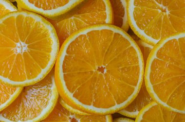 Gıda ve reklam tasarımı için canlı bir narenciye arkaplanı oluşturmak için düzgün sıralanmış parlak taze portakal kamaları..