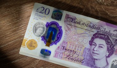 Tahta yüzeyde 20 pound 'luk banknot yığını var. Nakit, para ve hisse senedi ve finansal fotoğrafçılık için kişisel finans kavramı.