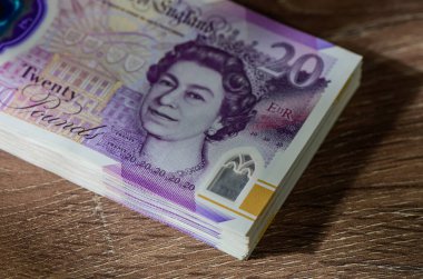 Kırsal ahşap masada 20 GBP faturası yığını. Finans, kişisel tasarruf ve hisse senedi fotoğrafçılığı için nakit kavramı.