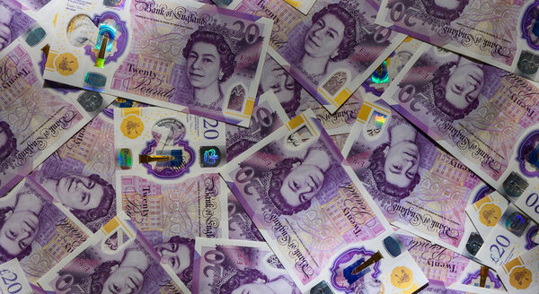Много 20 фунтов стерлингов разбросанных по столу. Концепция денежных средств, денег и финансов для фотографирования акций и финансовых иллюстраций.