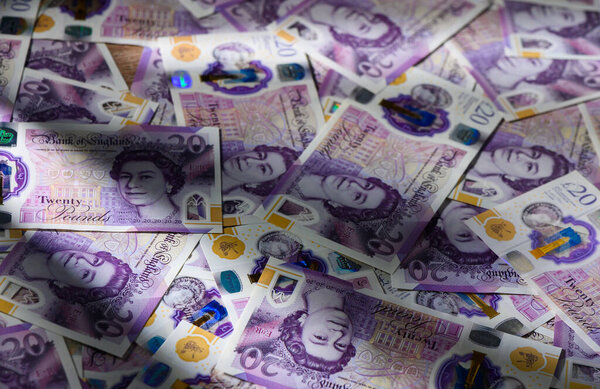 20 банкнот GBP случайно разбросаны по столу. Концепция денежных средств, денег и финансов для фотографирования акций и финансовых иллюстраций.