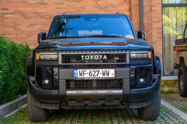 Tiflis, Gürcistan, 10.29.2025. Siyah Toyota SUV bir konut kompleksinin yanına park edilmiş. Araba dokusu ve kentsel arkaplan açıkça görülüyor.