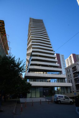 Beyaz balkonları ve geniş pencereleri olan modern piramit şekilli bir bina. Geometri, ışık ve minimalizmi birleştiren eşsiz mimari tasarım. Çağdaş şehir tarzı ve yaratıcı mimarinin bir sembolü..