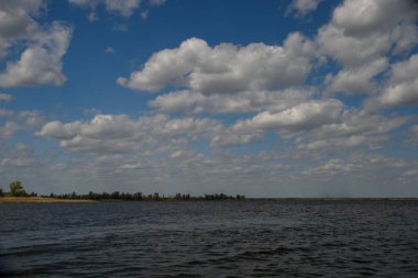 Dinyeper Nehri manzaralı sakin su yansıtan bulutlar, arka planda nehir kıyısı, huzurlu nehir manzarası.