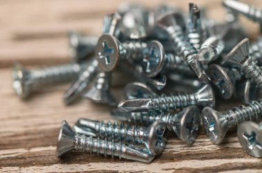 Çatı vidaları eski ahşap masaya saçılmış.