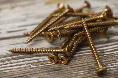 Eski ahşap bir masa üzerinde bronz vidalar yığını, DIY, atölye ve inşaat aracı fotoğrafçılık için mükemmel.