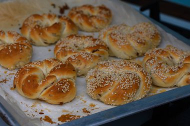 Pişirme tepsisinde susam tohumlarıyla kaplı taze ev yapımı Türk simit. Altın kabuklu ve lezzetli aromalı geleneksel Türk hamur işi..