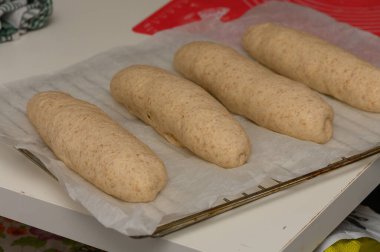 Ev yapımı Graham ekmeğine yumurta banyosu yapan bir kadının yakın plan bir mutfak ortamında pişirme tepsisi üzerindeki ekmek somunları..