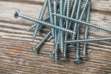 Ahşap bir masaya saçılmış parlak metal vidalar yakın plan, DIY, inşaat ve donanım fotoğrafçılık için mükemmel.