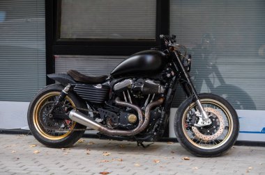 Tiflis, Georgia11,06.2025 siyah motosiklet bir apartmanın zemin katındaki bir kafenin girişine park edilmiş. Krom detaylara sahip modern bisiklet şehir ışıklarını yansıtır. Şehir atmosferi ve yaşam tarzı.