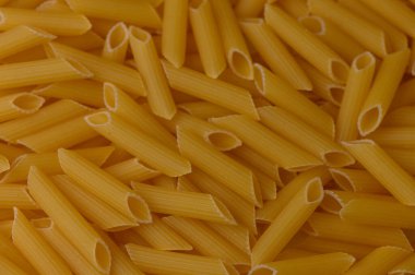 Kuru meze makarna desenli bir arka plan oluşturuyor. Altın sarısı tonlarda İtalyan yemeği konsepti.