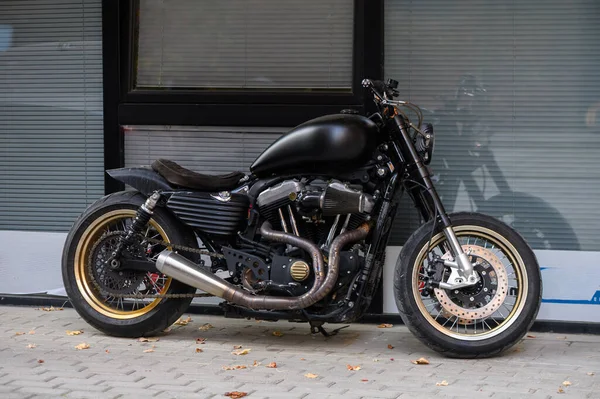 Tiflis, Georgia11,06.2025 siyah motosiklet bir apartmanın zemin katındaki bir kafenin girişine park edilmiş. Krom detaylara sahip modern bisiklet şehir ışıklarını yansıtır. Şehir atmosferi ve yaşam tarzı.