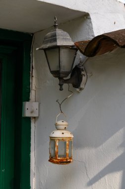 Geleneksel bir Kıbrıs Rum evinin dokulu taş duvarına iliştirilmiş klasik eski bir fener..