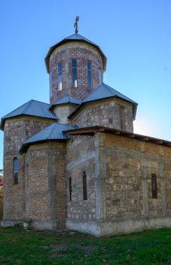 Eski kilise, kaldırılmış taş cepheli ve kaldırımlı camlı kaldırım taşı sokağında. Sıcak gün ışığı ve komşu ev gölgeleri, kültürel fotoğraflar için canlı bir arkaplan oluşturarak dokuyu ön plana çıkarıyor. 