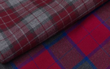 Kırmızı, siyah ve beyaz tonlarda yün desenli tartan kumaş. Birleşmiş çizgiler ve doku İskoç motifleri ve tasarımı için klasik bir arkaplan oluşturur