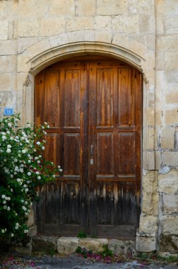 Kırsal bir cazibeyle eskimiş ahşap kapı, sakin bir köydeki geleneksel Kıbrıs evleri için tipik bir durum..