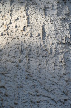 Sert dokusu, küçük gözenekleri ve hafif çatlakları olan beton duvarın makro görüntüsü. Nötr gri ton ve mat yüzeyi modern tasarım ve kentsel bileşimler için çok yönlü bir arkaplan oluşturur