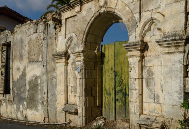 Geleneksel Kıbrıs Rum ev duvarı, taştan yapılmış ve kırsal Akdeniz tarzını yansıtan eski ahşap kapılara sahip..