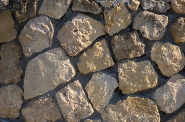 Yıpranmış taşlar, doğayı ve işçiliği harmanlayan parlak bir zemin üzerine toprak dokusunu sunar..