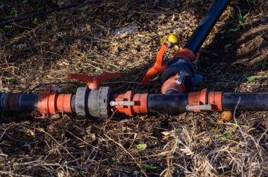 Plastik su boruları, bahçeye su dağıtan bir T-joint aracılığıyla bağlanıyor. Arka bahçedeki ya da tarımsal ortamdaki verimli su kaynakları için sulama sistemi.