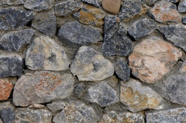 Engebeli taş bir duvar, zengin bir renk ve şekil duvar halısı sergiliyor. Seyircileri, doğanın malzemelerinin ve işçiliğinin organik güzelliğini takdir etmeye çağırıyor..