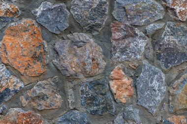 Topraksı tonlarda çeşitli taşlar kırsal bir duvar oluşturur, sakin bir açık havada doğanın sanatını gözler önüne serer..