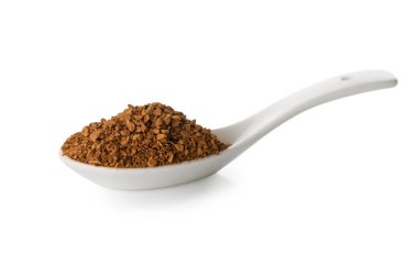 A white ceramic spoon holding a generous heap of dark instant coffee granules. The textured surface of the coffee creates visual interest against the smooth ceramic in this close-up shot.