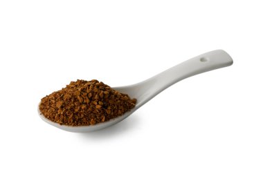 A white ceramic spoon filled with dark instant coffee granules, isolated on a neutral background. The contrast between the pure white spoon and rich brown coffee creates a minimalist composition.