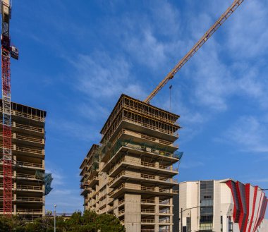 Hassasiyet ve güce odaklan. Çekim, vincin beton blokları, metal yapıları veya biçimlendirmeyi hareket ettirdiği anı yakalar. Bu da sürecin koordinasyonunu ve teknolojik doğasını gösterir..